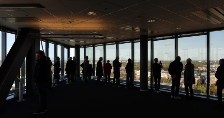 Man ser silhuetterna av människor som står högst upp i Kista Scvience Tower och tittar ut.
