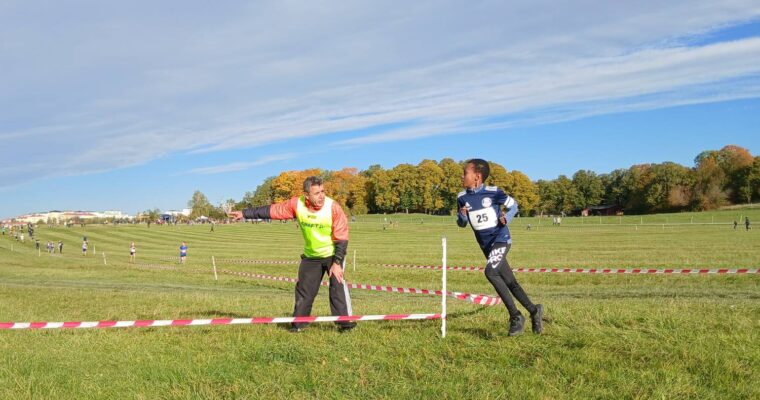 En pojke springer på ett stort fält och en funktionär visar vägen.