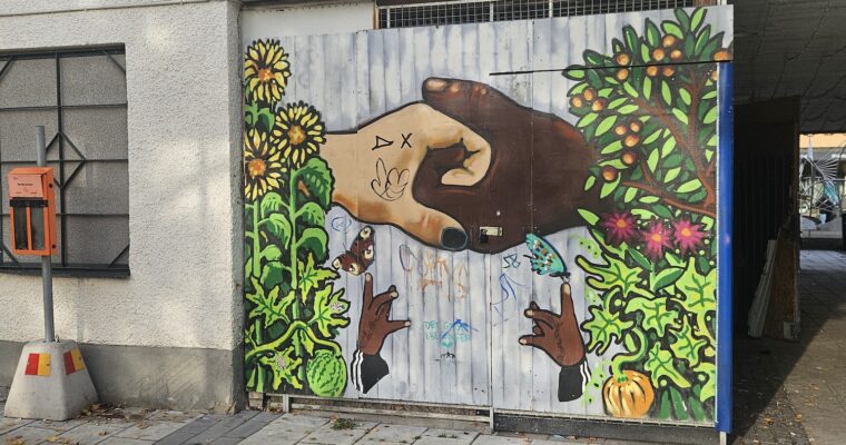 En vit hand och en brun hand håller i varandra på en väggmålning.