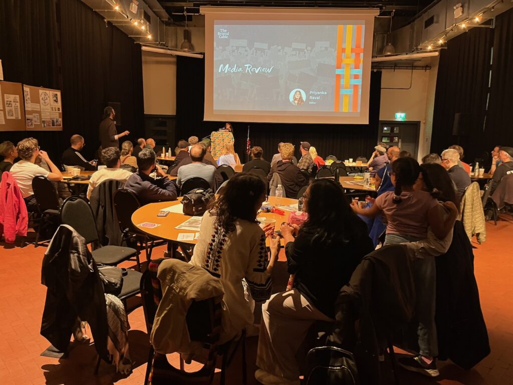 Människor i en mörk lokal ser tidningens resultat i ett bildspel.