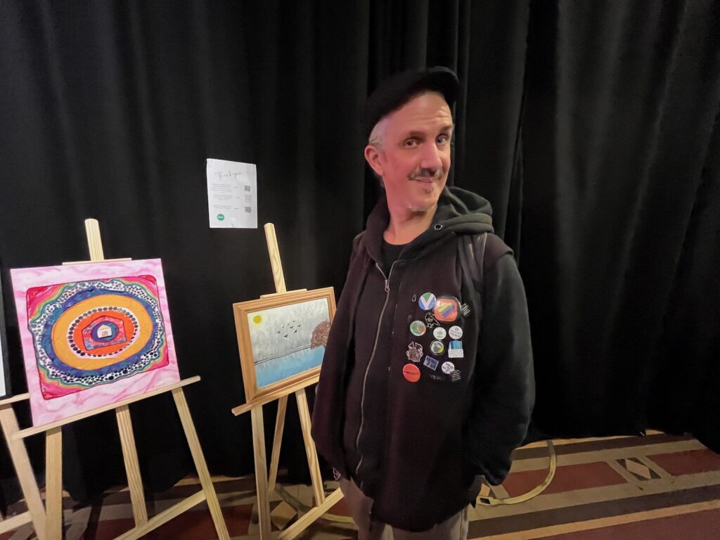 En man i keps och med en massa pins på jackan.