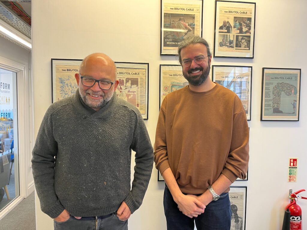 Två leende män, båda har asiatiskt urspring och glasögon. De ler.