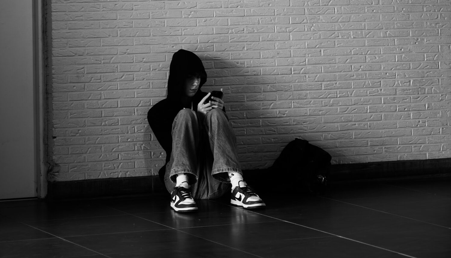 Barn sitter på golvet och kollar i mobilen