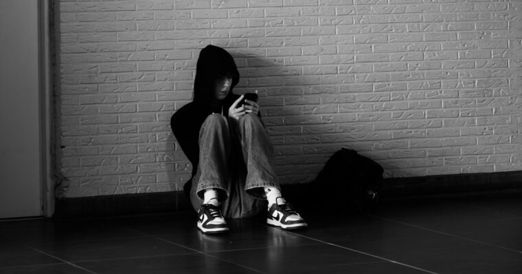 Barn sitter på golvet och kollar i mobilen