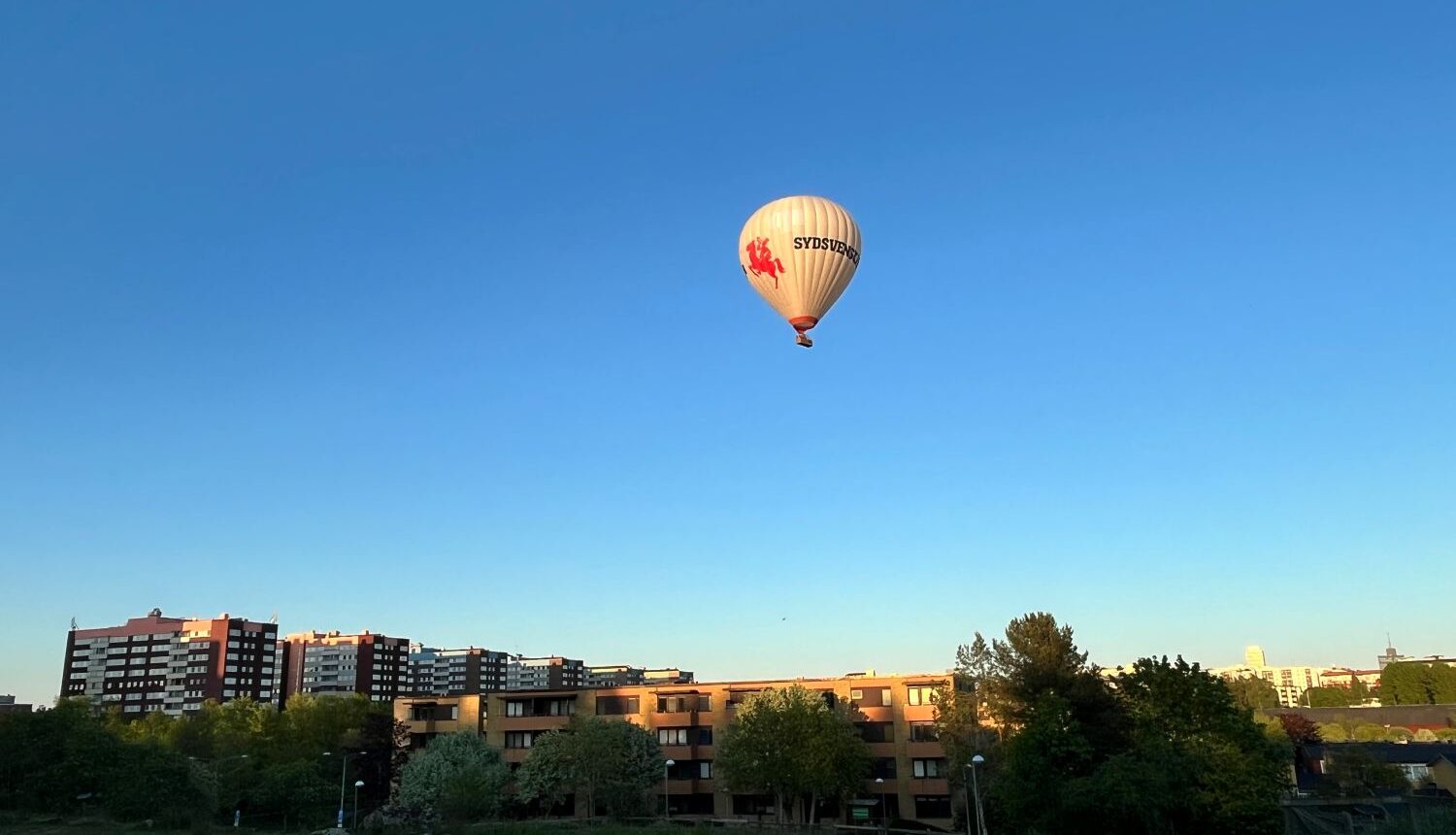 luftballong flyger över en stadssiluett i förorten