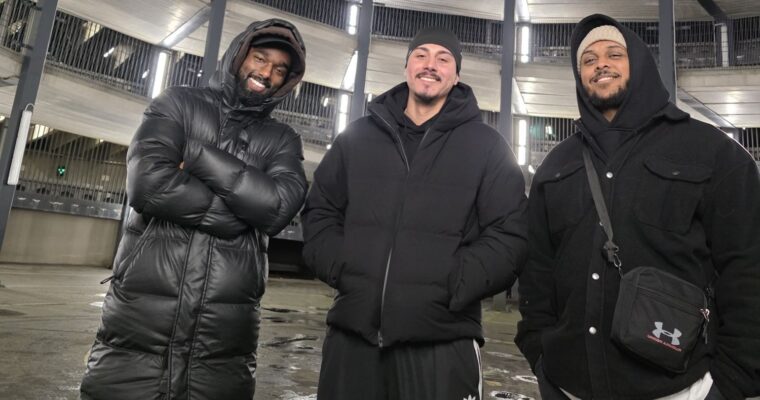 tre grabbar i vinterkläder med ortenstil och ett parkeringshus i bakgrunden