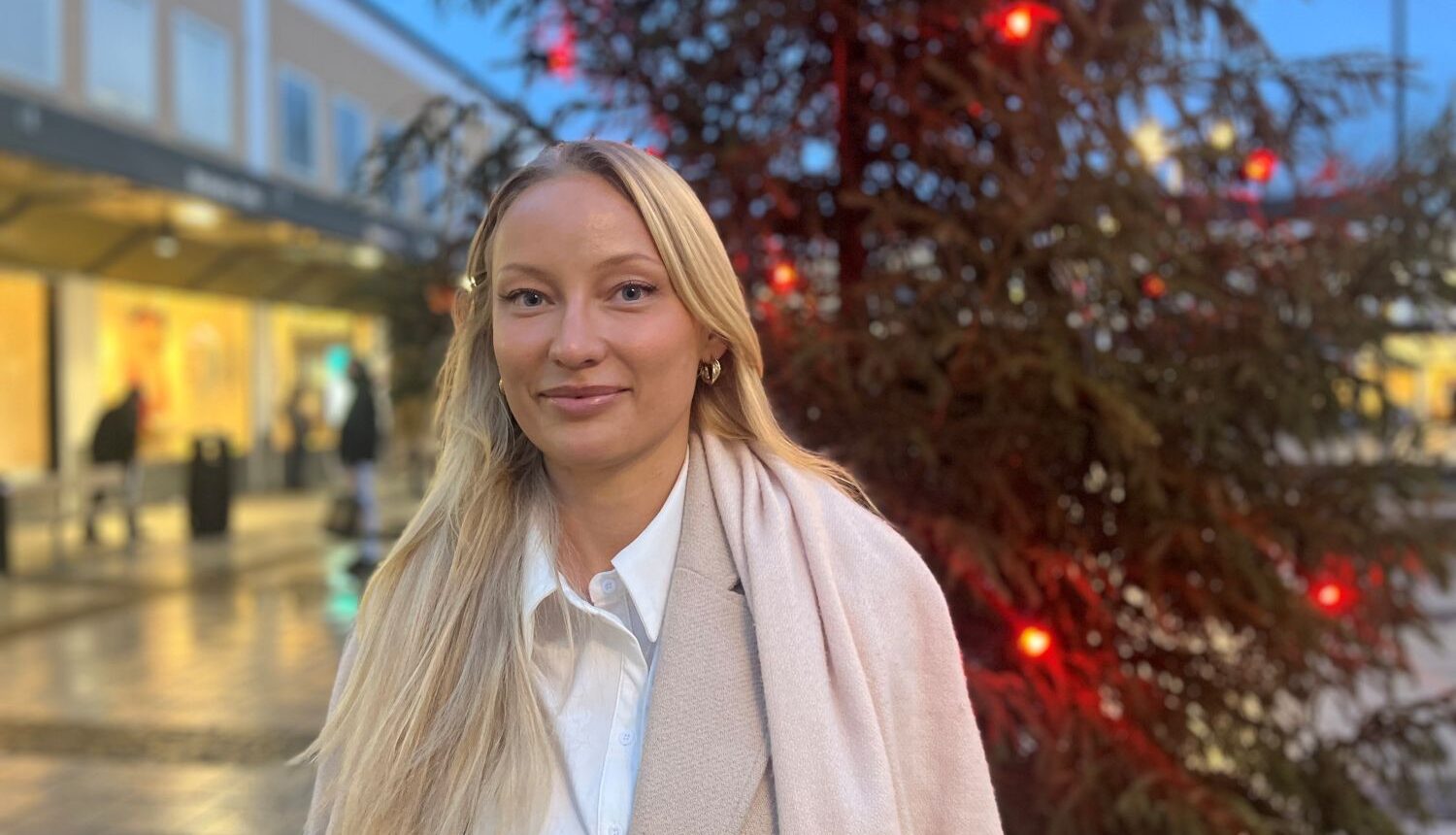 ung kvinna står framför en julgran med röda lampor i