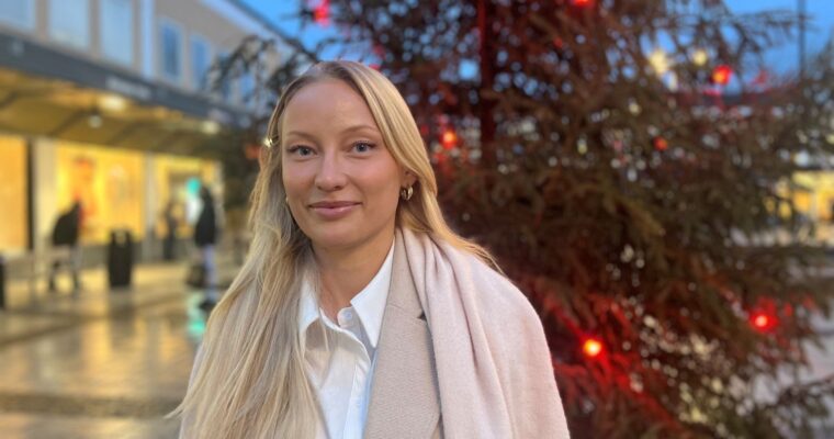 ung kvinna står framför en julgran med röda lampor i