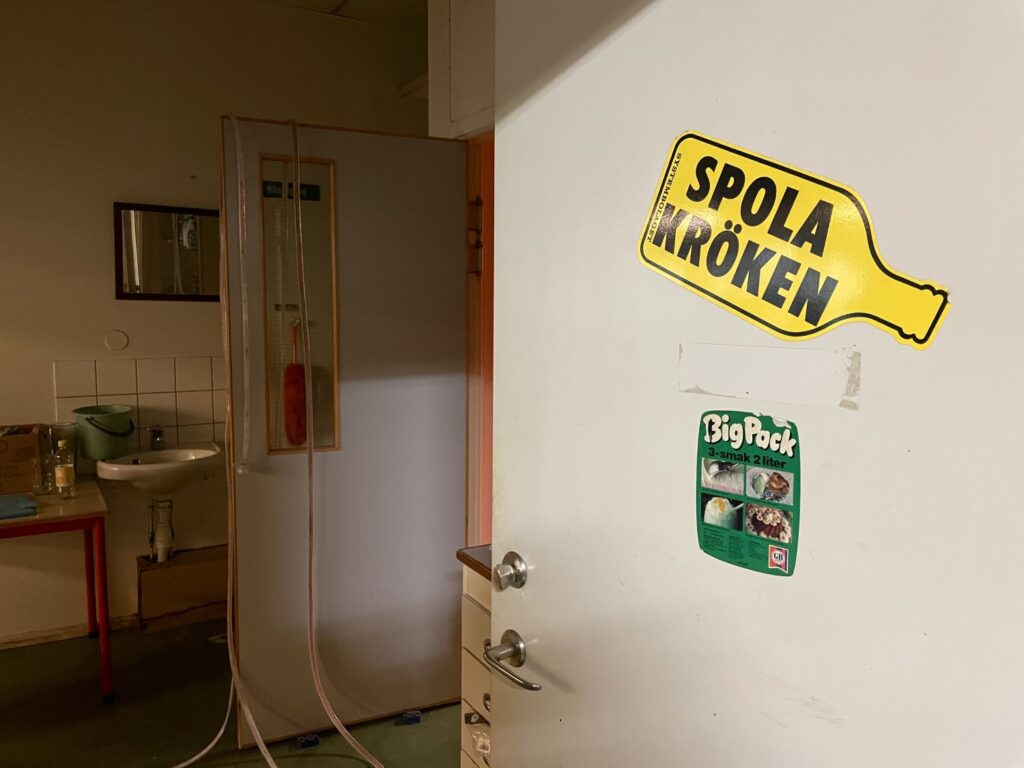 Klistermärken och skyltar på väggen vittnar om platsens historia.