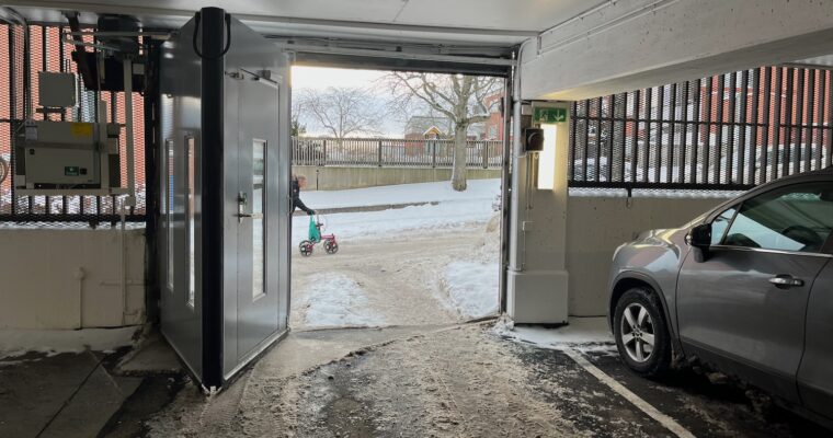 En bild inifrån garaget, man ser någon som drar en rollator utanför.