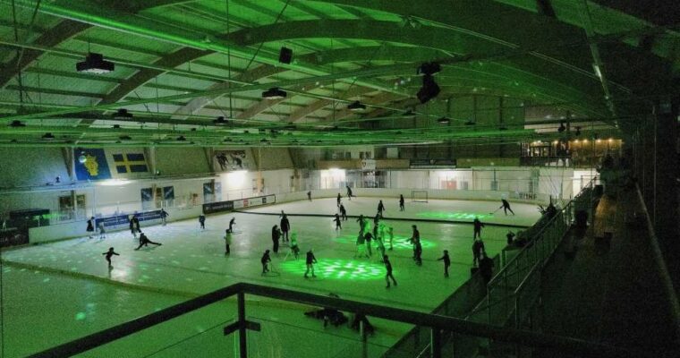 grön belysning över ishall och skridskoåkare