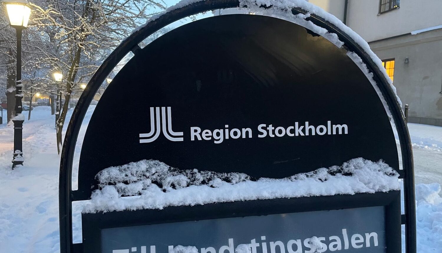 En snöig skylt som det står Region Stockholm på.