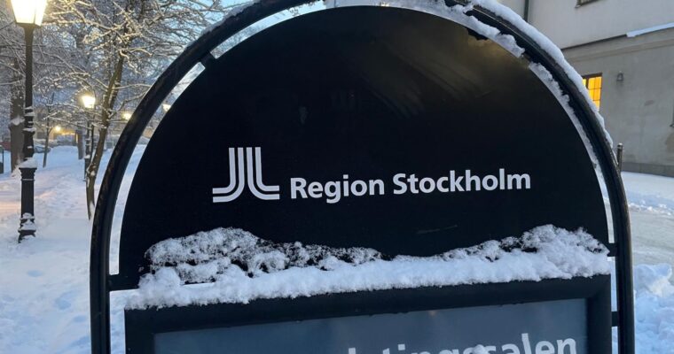 En snöig skylt som det står Region Stockholm på.