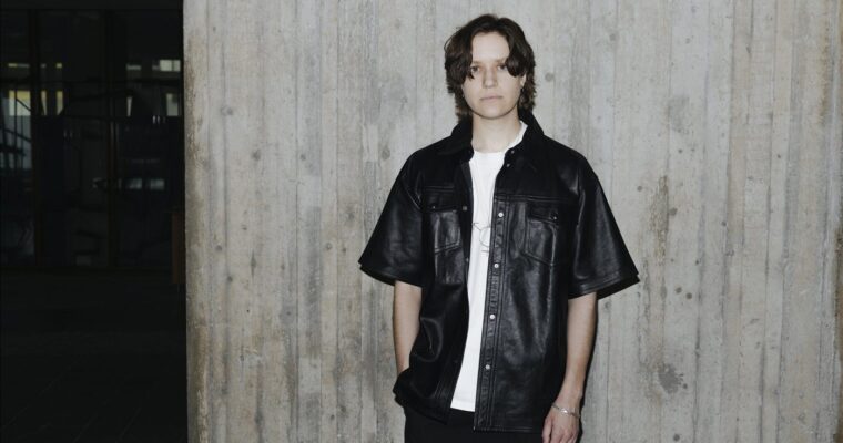 Silas Aliki, stående framför en betongvägg