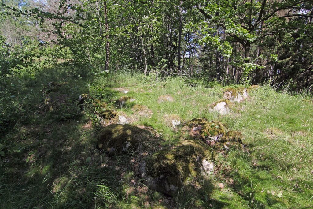 Trafikplats Hjulsta. Kvadratisk gravsättning på den skogsklädda höjden.