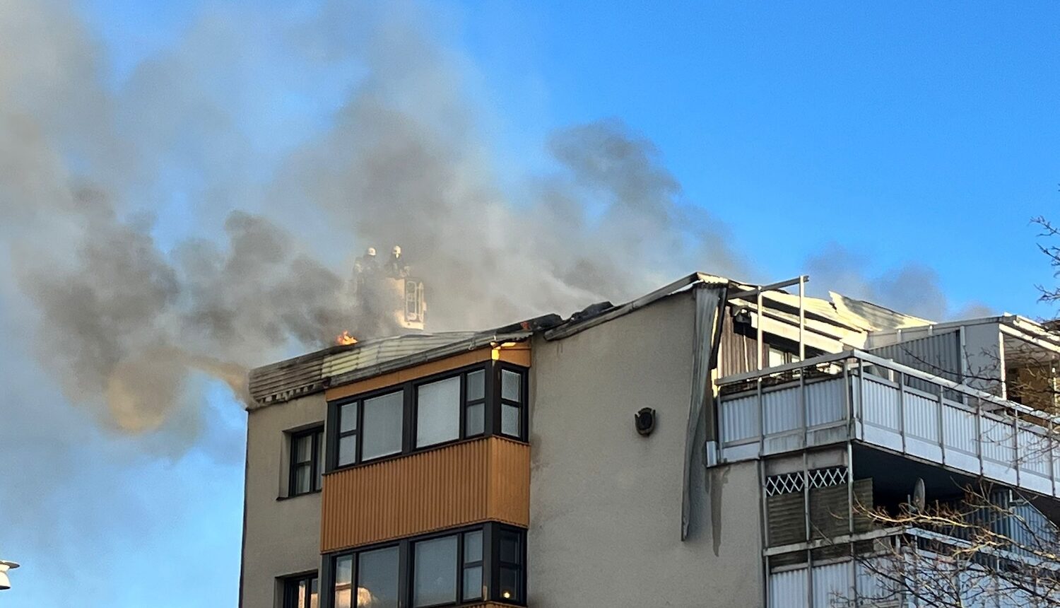 Eldslågor och rök , två badnmän på taket.