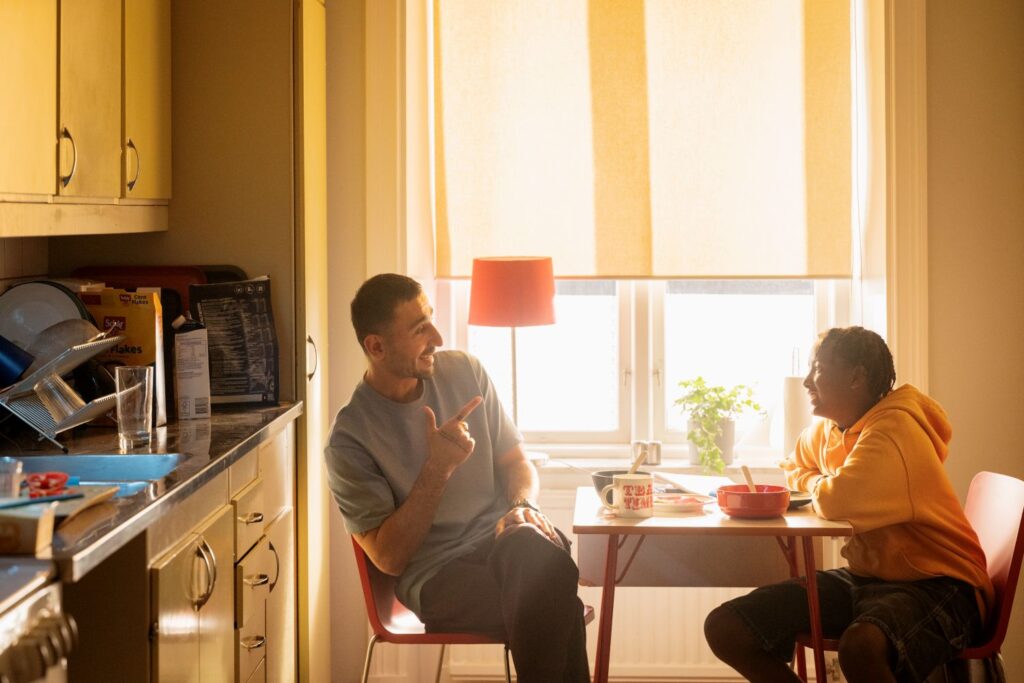 en man och en kille sitter ned och pratar vid ett matbord i ett kök