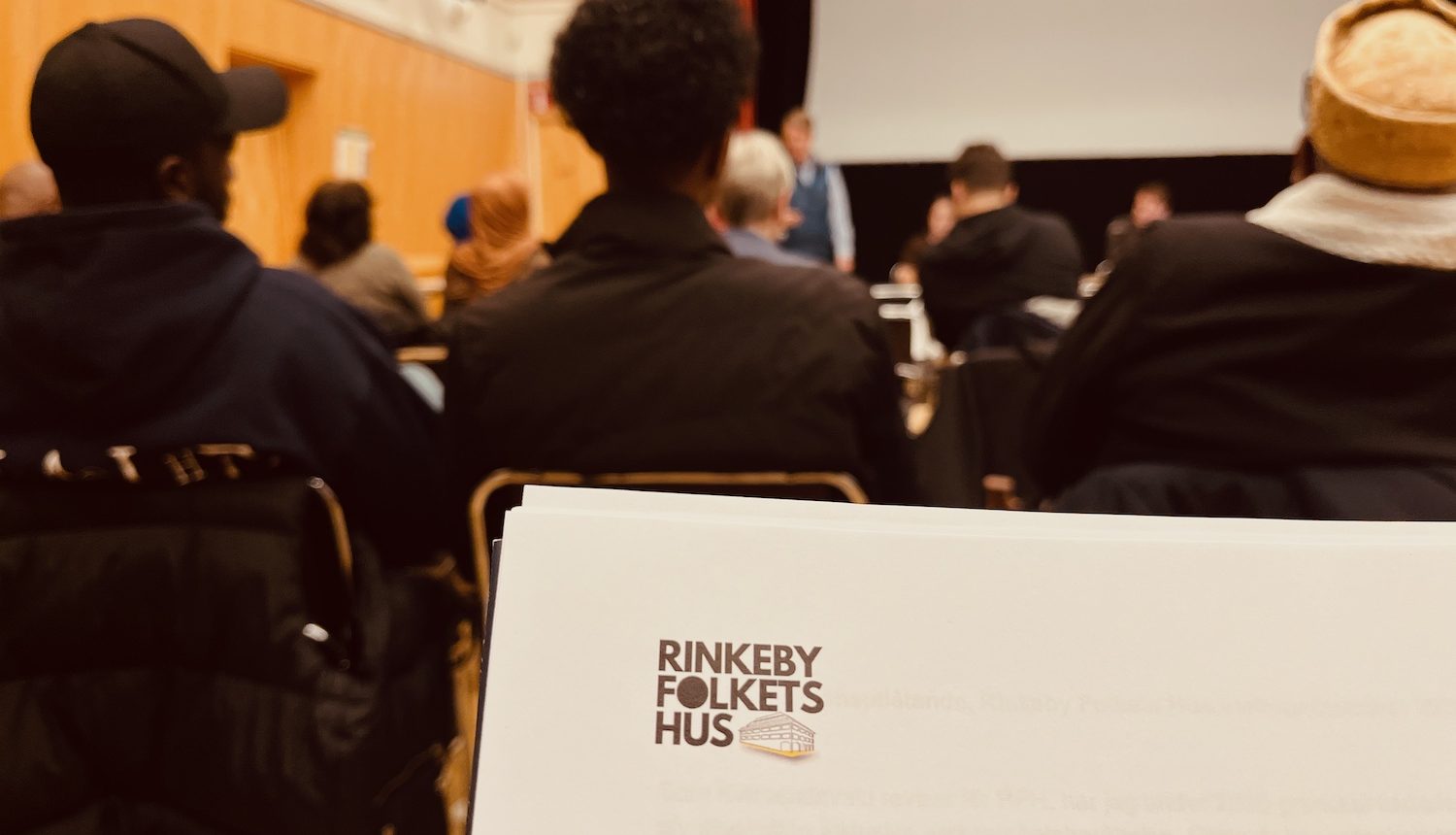 Dagordningen syns på papperet och publiken lite suddigt i bakgrunden.