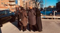 En grupp hyresgäster står på parkeringen på Hinderstorpsgränd, med ryggen åt fotografen.