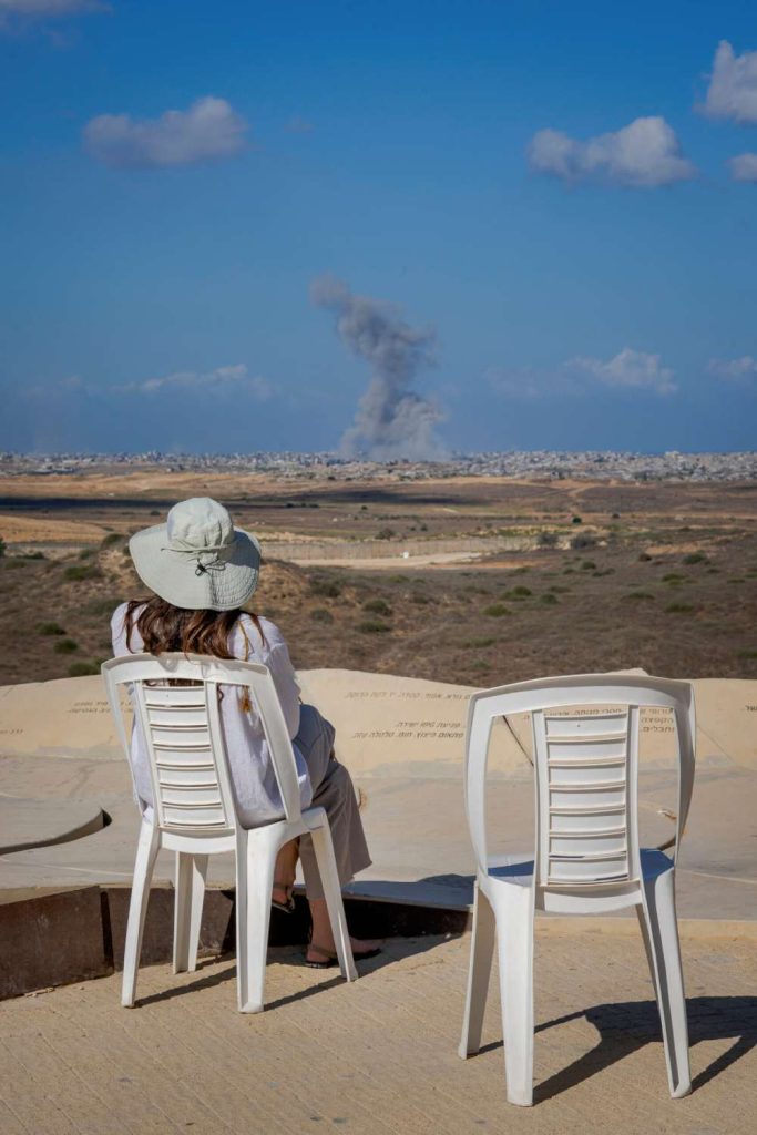 Årets bild 2025. Den sjunde oktober 2025 sitter en kvinna på en utsiktsplats i Sderot i södra Israel och tittar på en rökpelare som stiger upp mot himlen. Tre kilometer framför henne ligger norra Gaza. Foto: Alexander Mahmoud