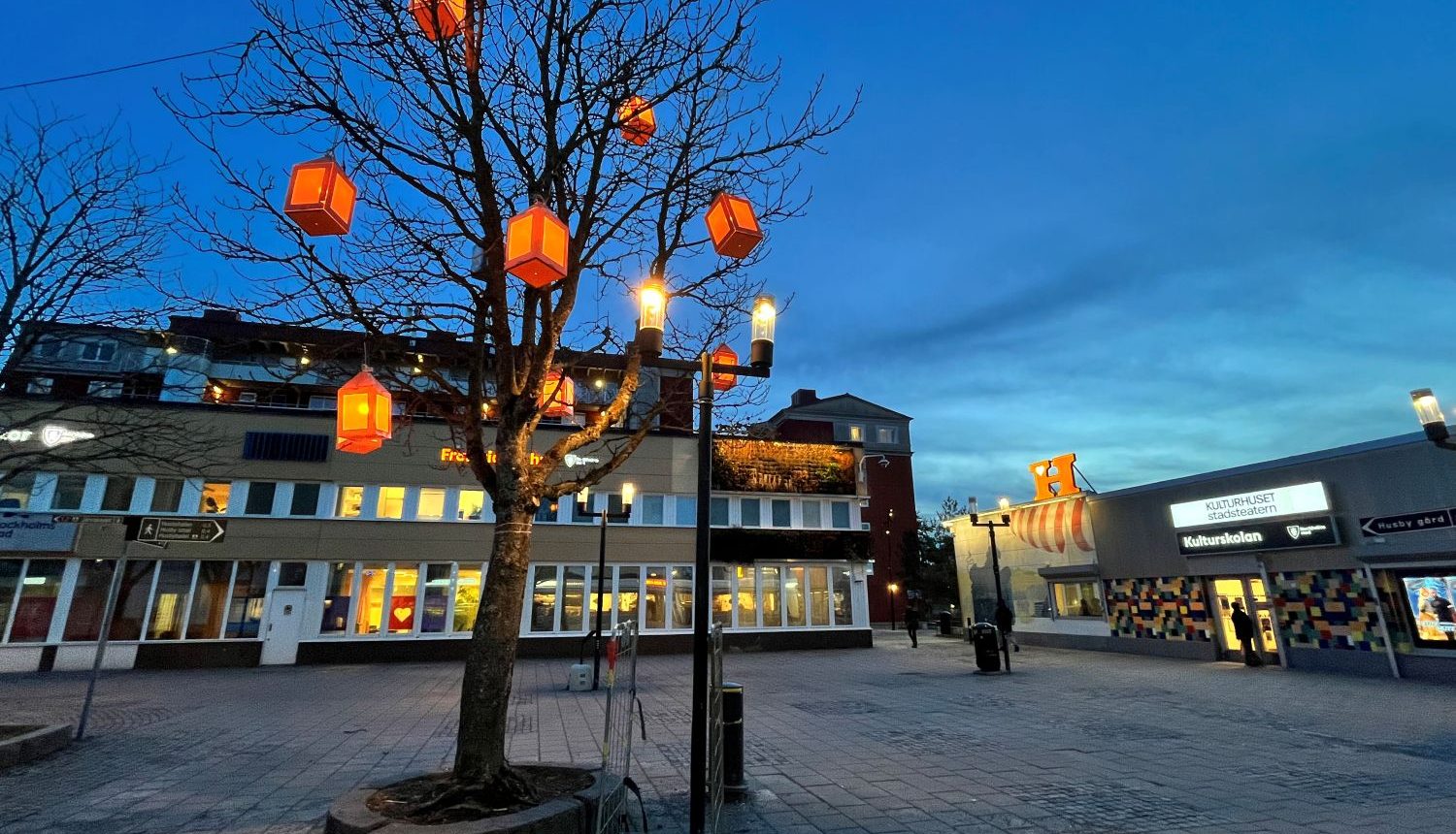eidpynt i form av lyktor hänger i träden på Husby torg