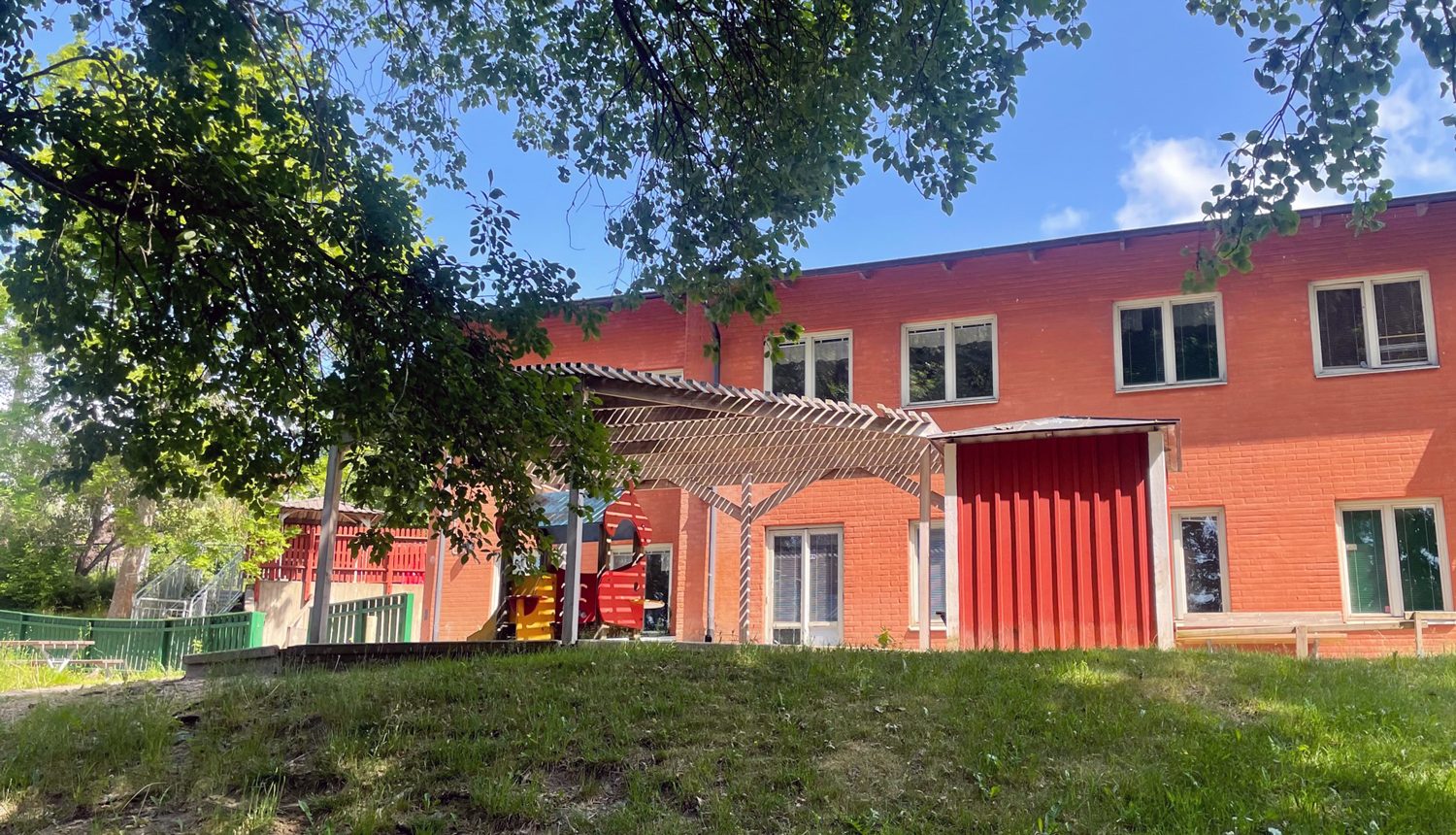 en förskolebyggnad med en lekplats framför