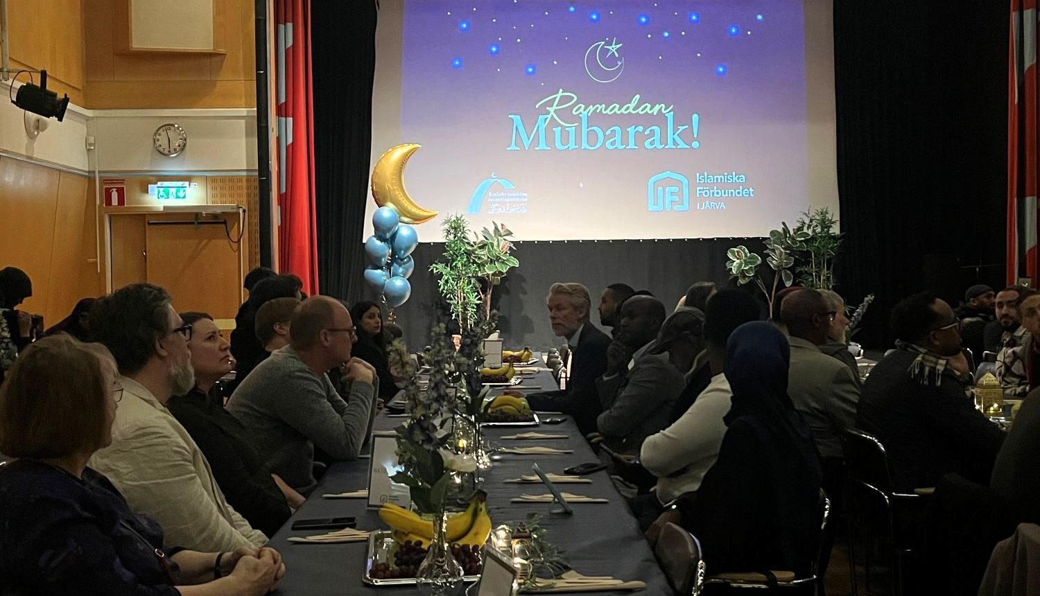 människor sitter vid långbord inför iftarmiddag