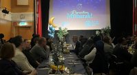 människor sitter vid långbord inför iftarmiddag