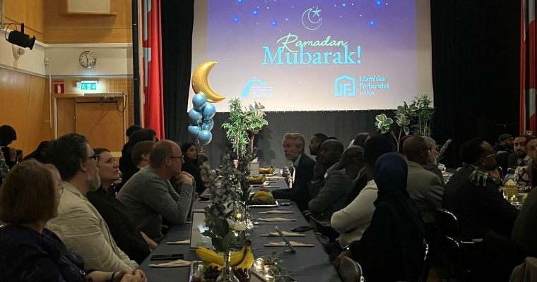 människor sitter vid långbord inför iftarmiddag