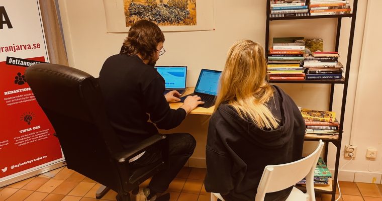 Två personer, en man och en kvinna, framför en dator vid ett bor på redaktionen.