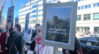 Demonstranter med plakat utanför mässan.