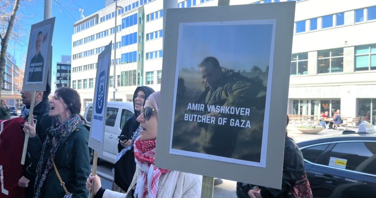 Demonstranter med plakat utanför mässan.