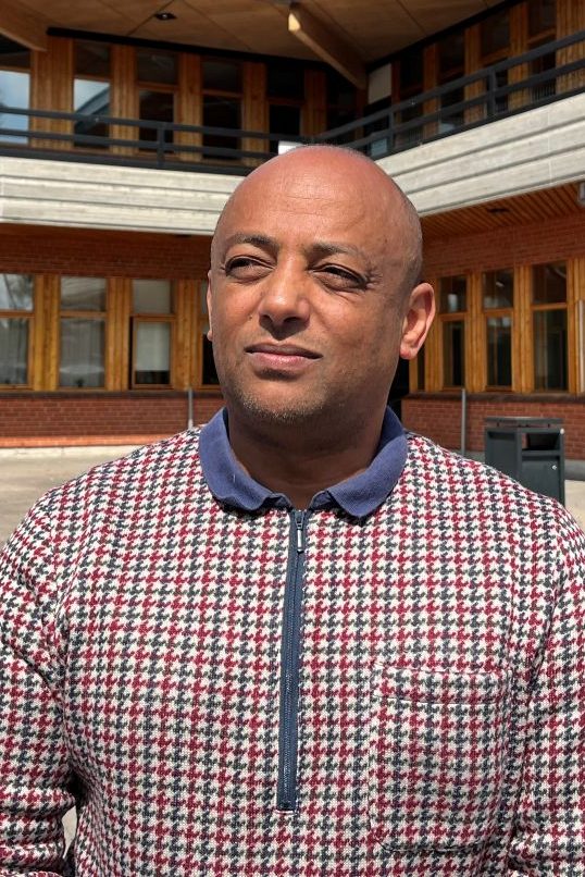 man står i solen framför en gymnasieskola