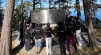ungdomar står hand i hand i ring runt ett minnesmonument för de som dödades på Utøya