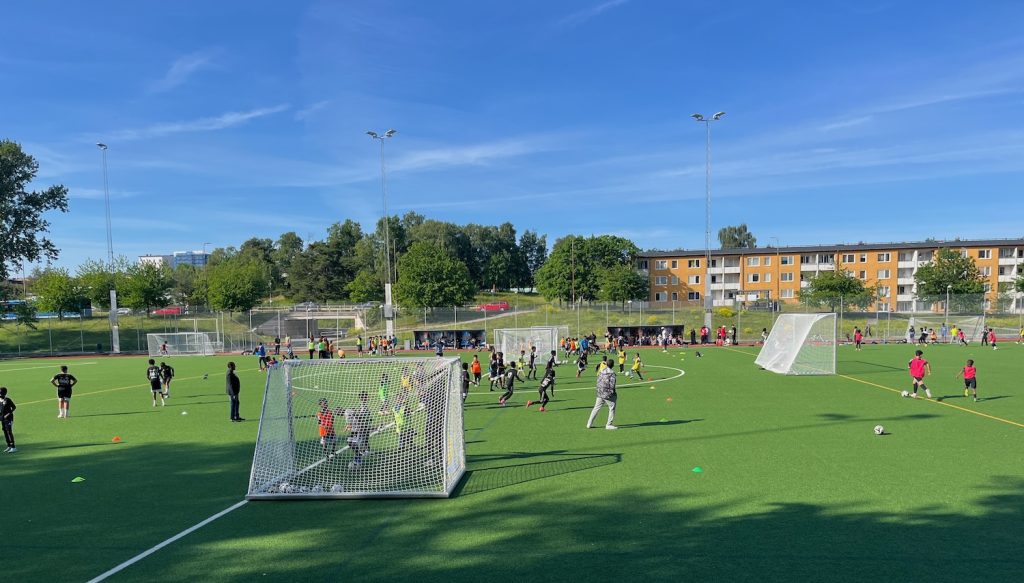 Massa barn och några vuxna på bollplanen.