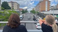 två kvinnor ser ut över en gata från en gångbro