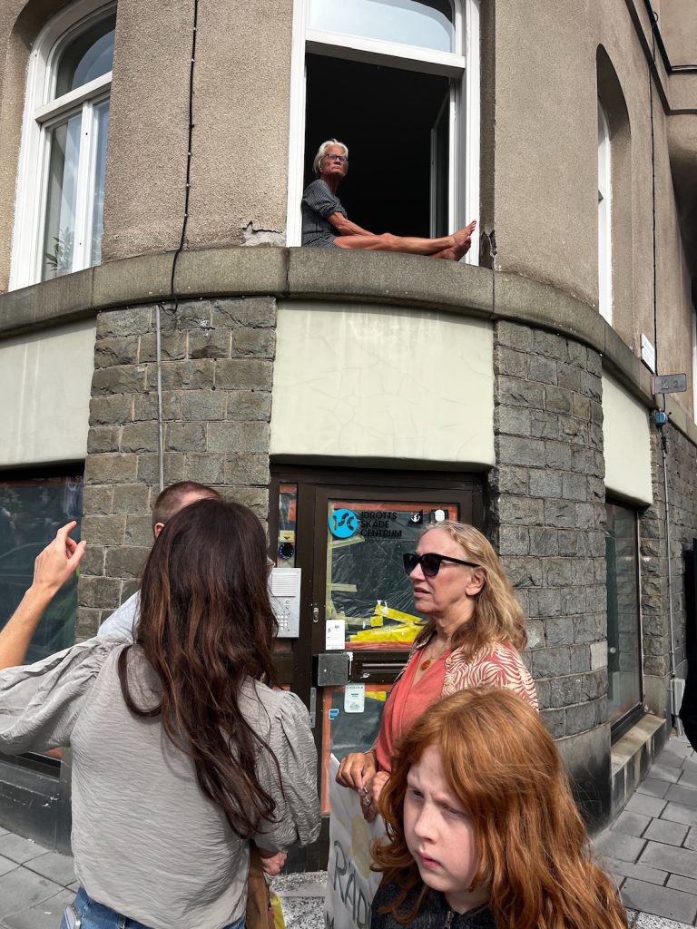 En dam sitter i fönstret i ett hus på Dalagatan och kollar på demonstrationen.
