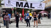 En kvinna står till höger under målgången vid Rinkeby torg