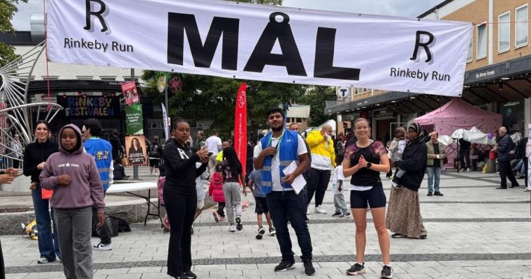 En kvinna står till höger under målgången vid Rinkeby torg