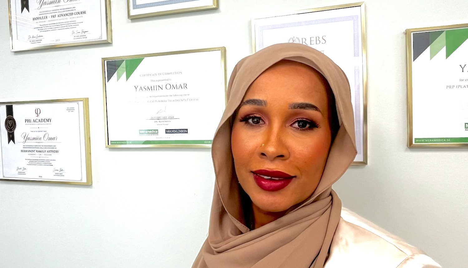 Yasmiin Omar fram väggen med diplom.