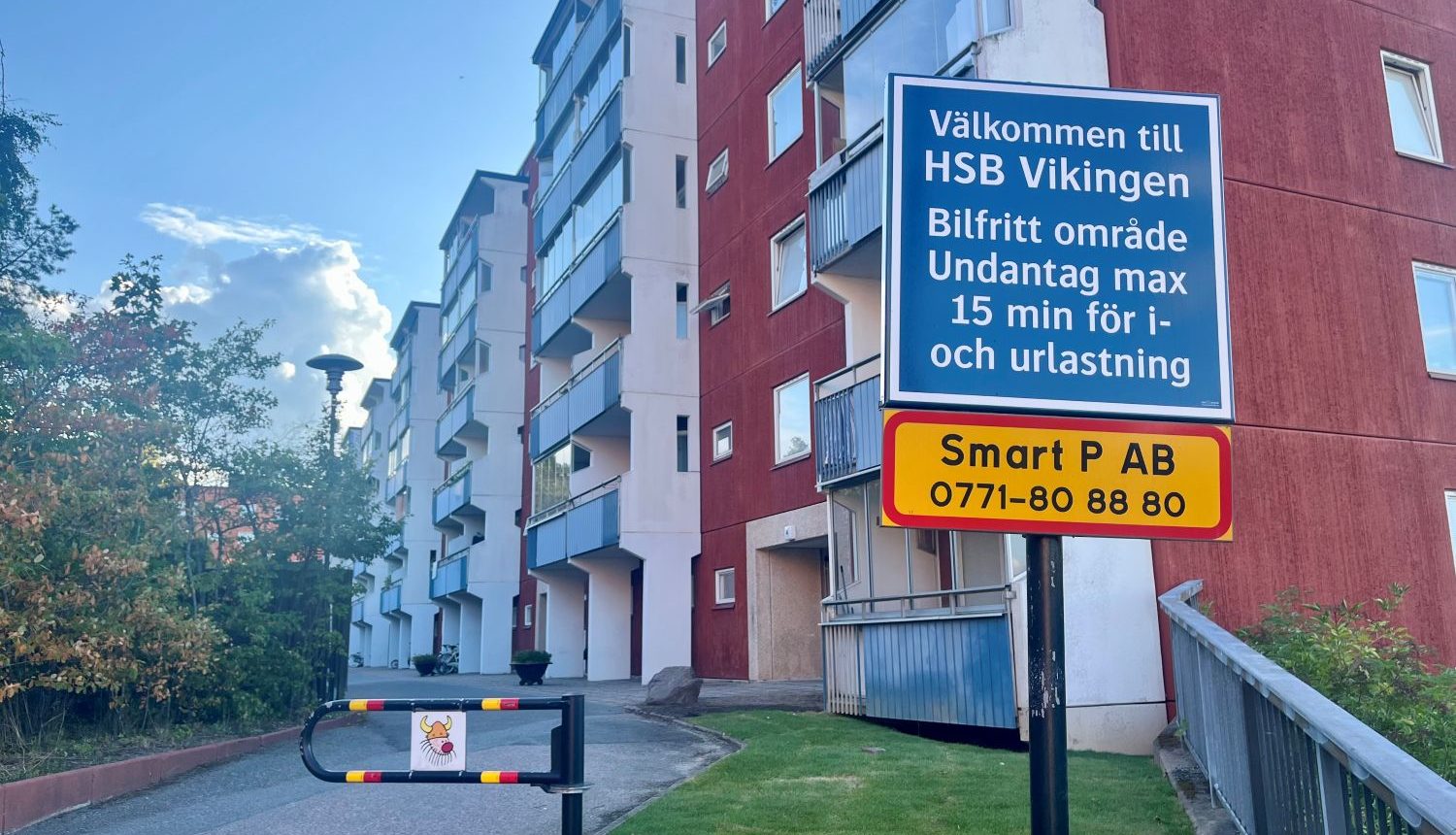 vägskyltar och bom framför höghus med bostadsrätter
