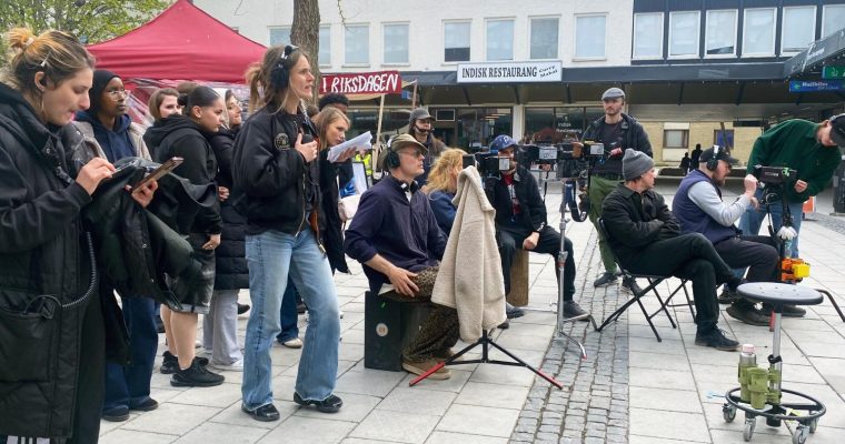Kamerorna är riktade mot ingången till Rinkeby torg när dagens sista scen spelas in.