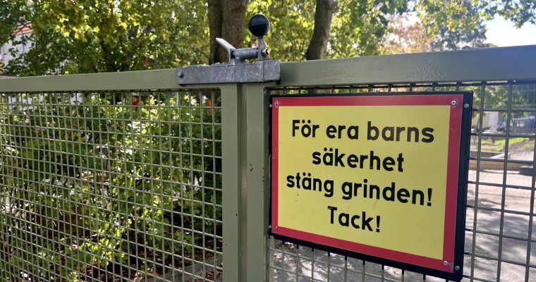 Skylt på grinden till en förskola som uppmanar till att hålla grinden stängd