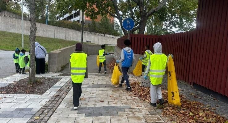 unga med reflexvästar plockar skräp och sorterar i säckar
