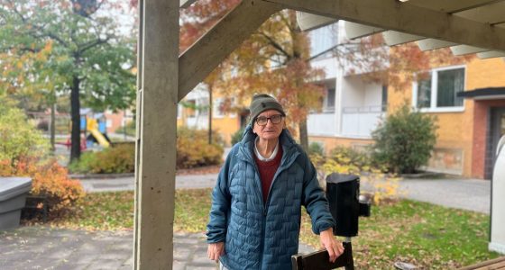 en man står och stödjer sig mot en trästol utomhus i höstväder