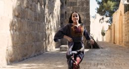 En flicka i traditionell palestinsk klänning springer på gatan